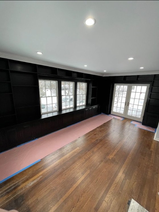 Freshly painted room with black built-in shelving and masked floors
